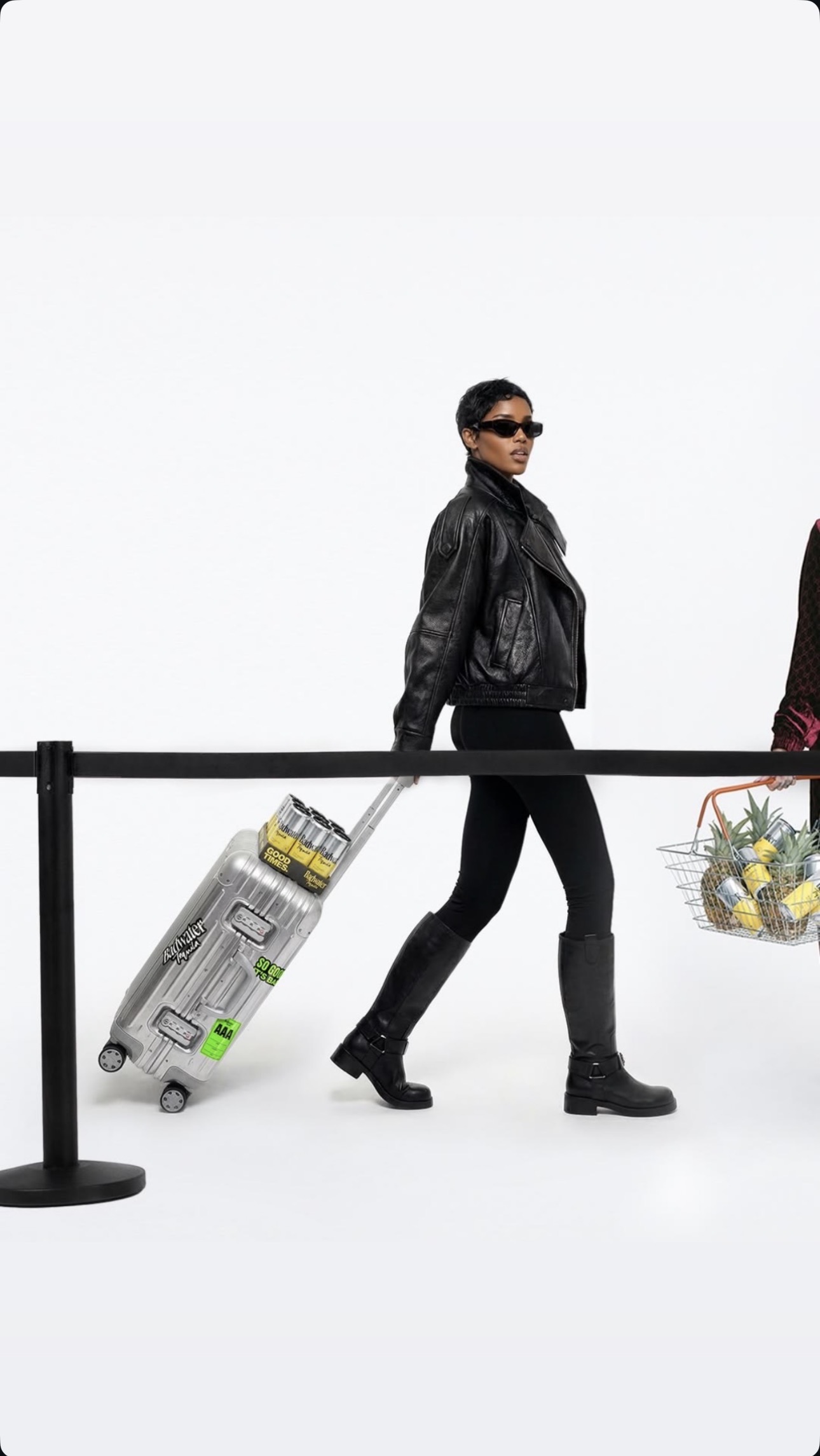 Model in a black leather jacket and boots pulling silver luggage