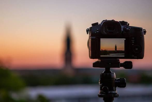 Camera on a tripod framing a city skyline at sunset