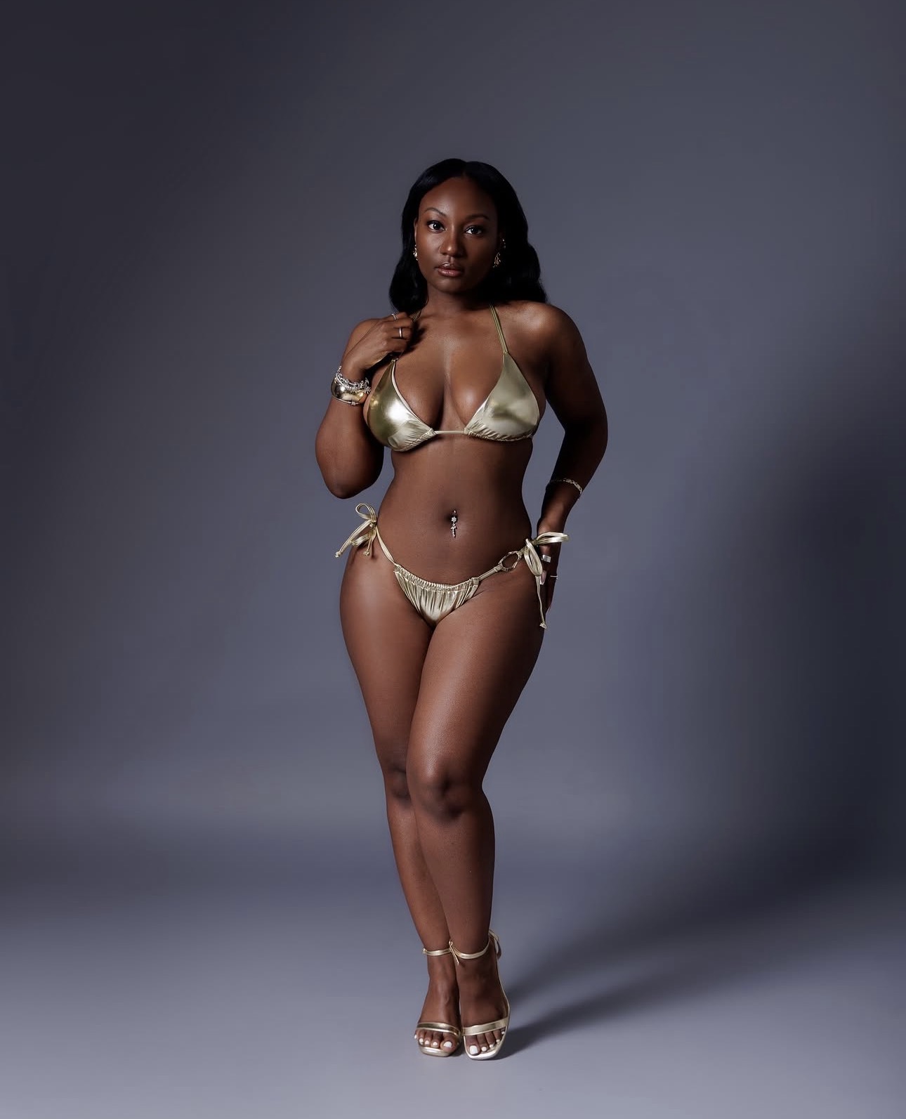 TDA model in a metallic gold two-piece outfit against a gray studio backdrop