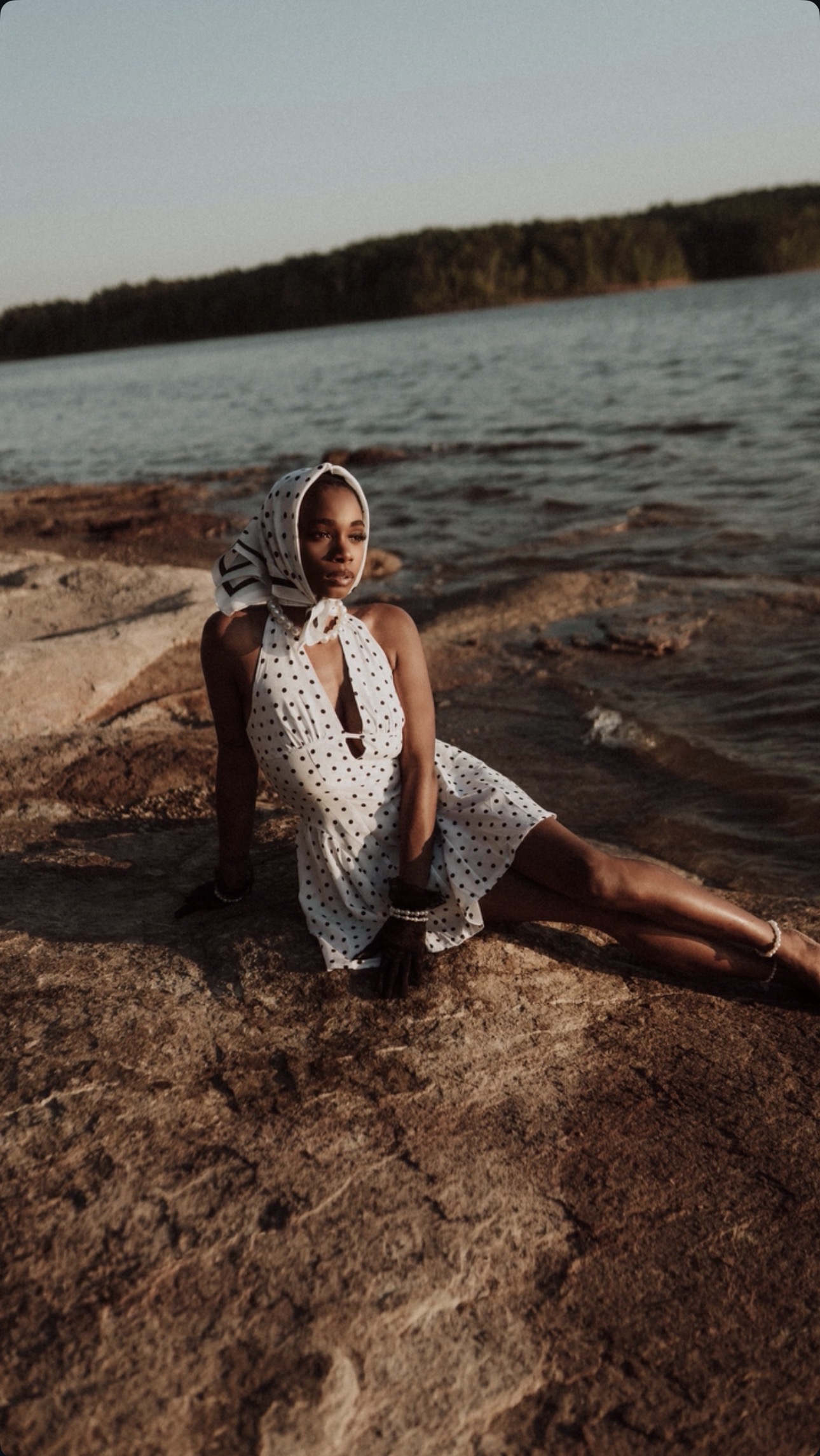 Model in a polka dot dress and headscarf on lake rocks